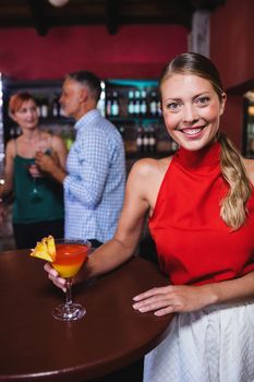 Portrait of woman enjoying cocktail in night club
