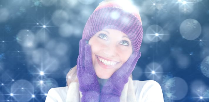 Cheerful young woman with cap and gloves in the winter  against shimmering light design on blue