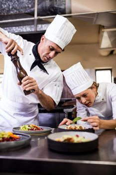 Male and female chefs preparing food in kitchen at hotel