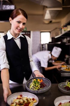 Female waitress holding plates with food in kitchen at hotel