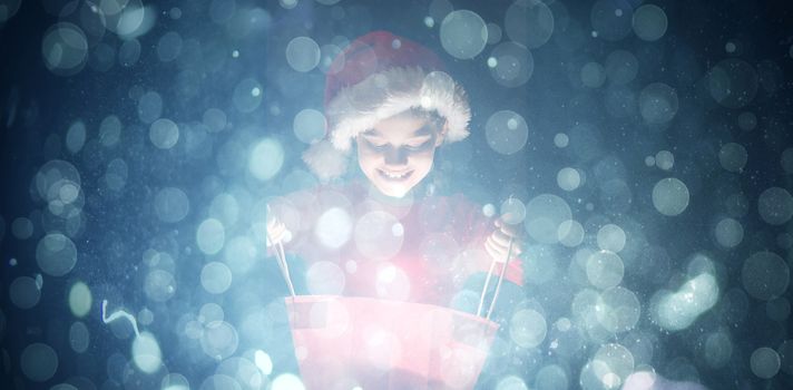 Little girl opening a magical christmas gift against blue abstract light spot design