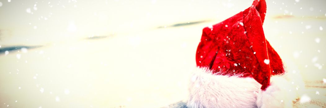 Snow falling against santa hat on the beach 