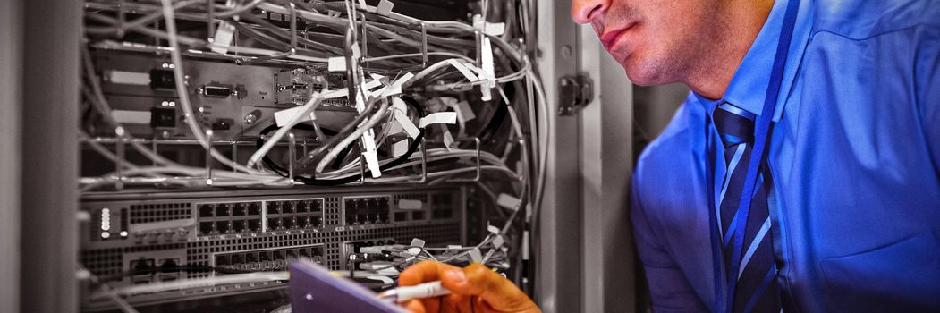 Technician maintaining record of rack mounted server on clipboard in server room