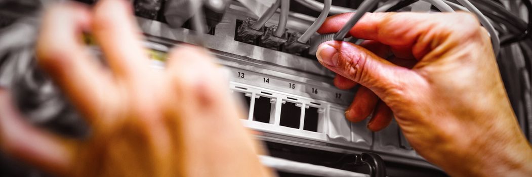 Technician plugging patch cable in a rack mounted server in server room 