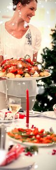 Cheerful woman bringing a roast chicken at table against snow falling