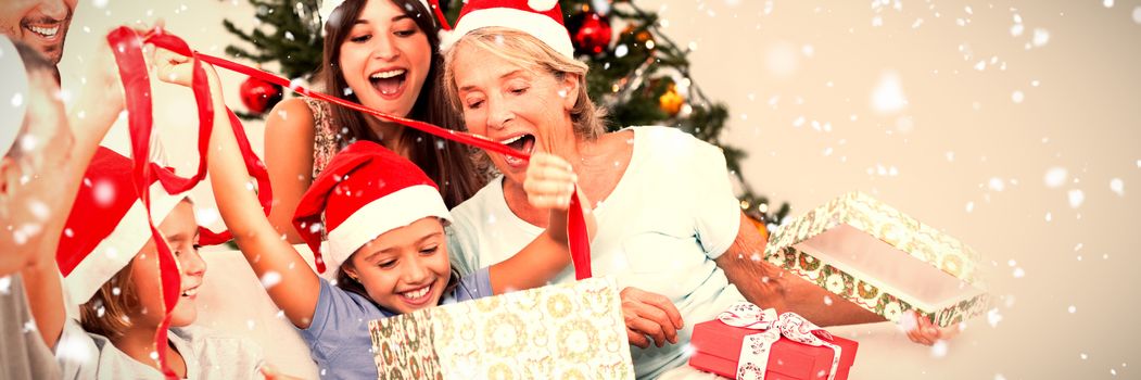 Happy family at christmas opening gifts together against snow falling