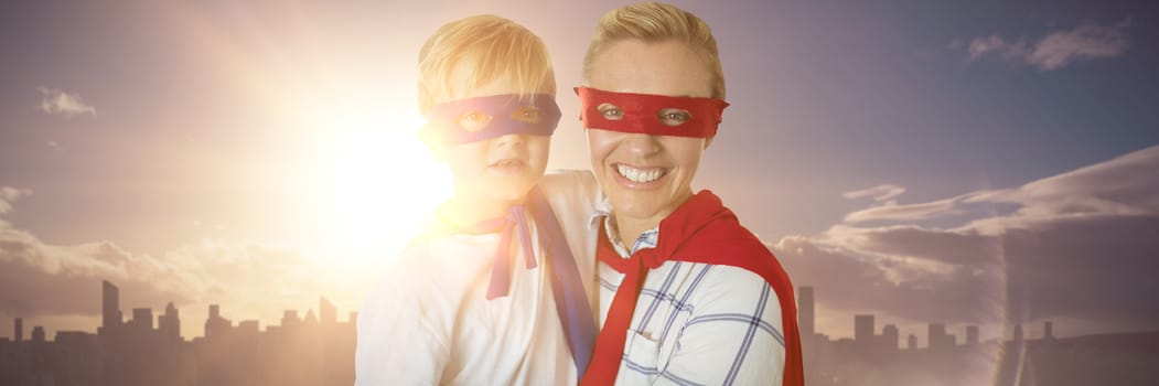 Mother and son pretending to be superhero against picture of city by sunrise