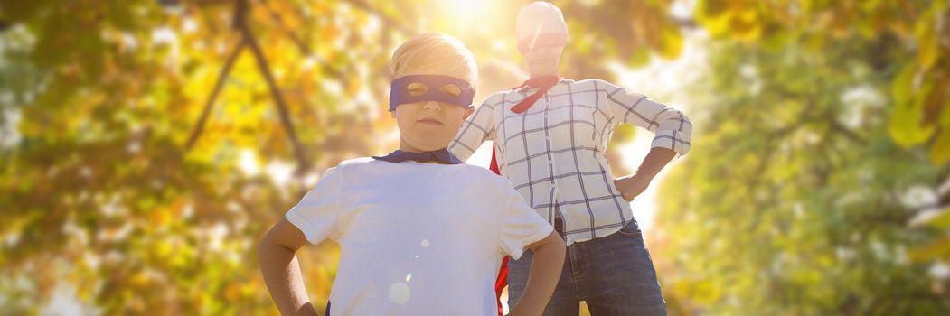 Mother and son pretending to be superhero against low angle view of back lit trees