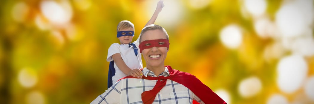 Mother and son pretending to be superhero against defocused image of tree