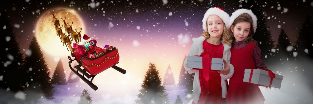 Cute girls with gifts against full moon over snowy landscape and house