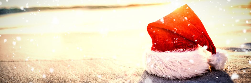 Snow falling against santa hat on the beach 