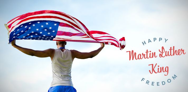 Rear view of sportsman holding american flag  against blue sky with clouds 