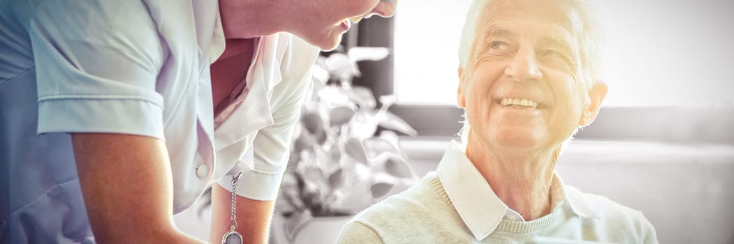 Female nurse showing medical report to senior man on digital tablet  at home