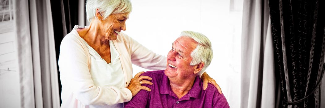 Senior couple looking at each other and smiling in living room