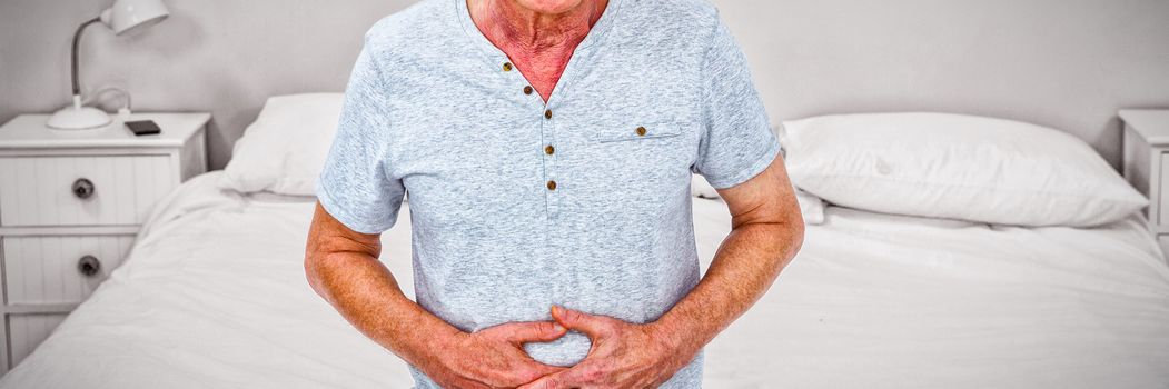 Sad senior man touching stomach while sitting at home