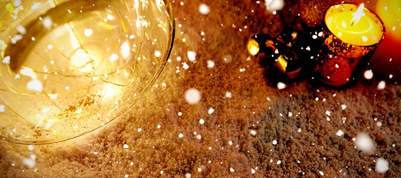 Snow falling against christmas candles in the snow