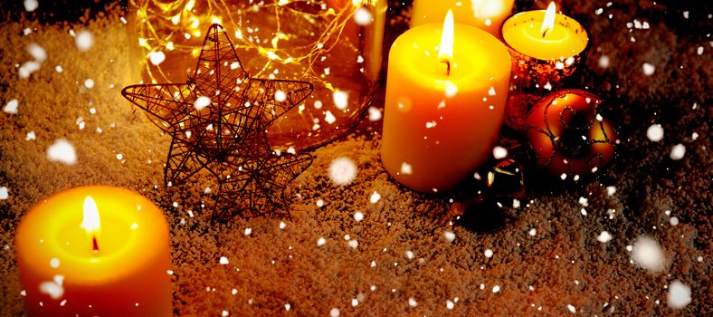 Snow falling against christmas candles and ornaments