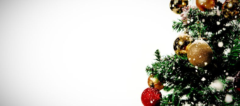 Snow falling against christmas decorations in tree 