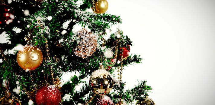 Snow falling against christmas decorations hanging in tree