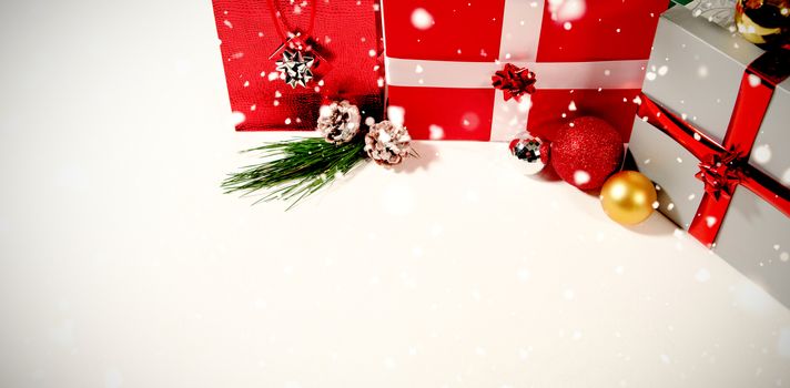 Snow falling against christmas gifts against white background