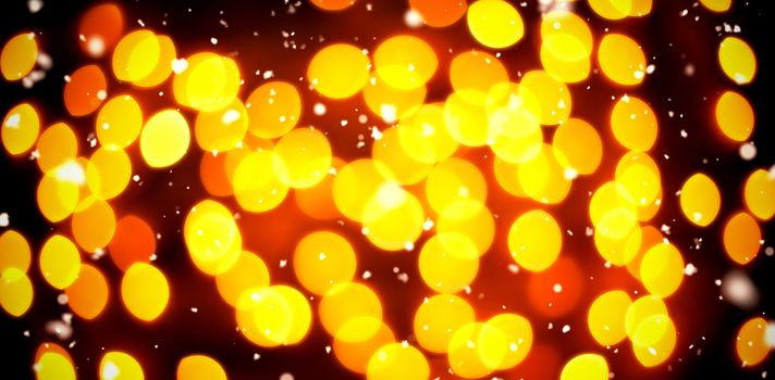Snow falling against unfocused yellow christmas light