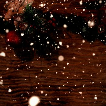 Snow falling against christmas ornaments on wood 