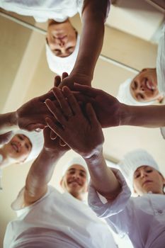 Group of chefs formig hands stack om kitchen at hotel