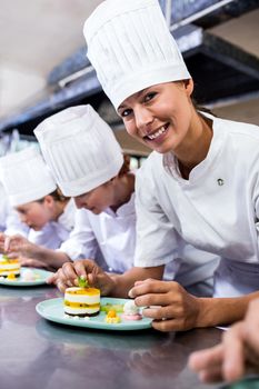 Group of chefs garnishing delicious desserts in a plate at hotel