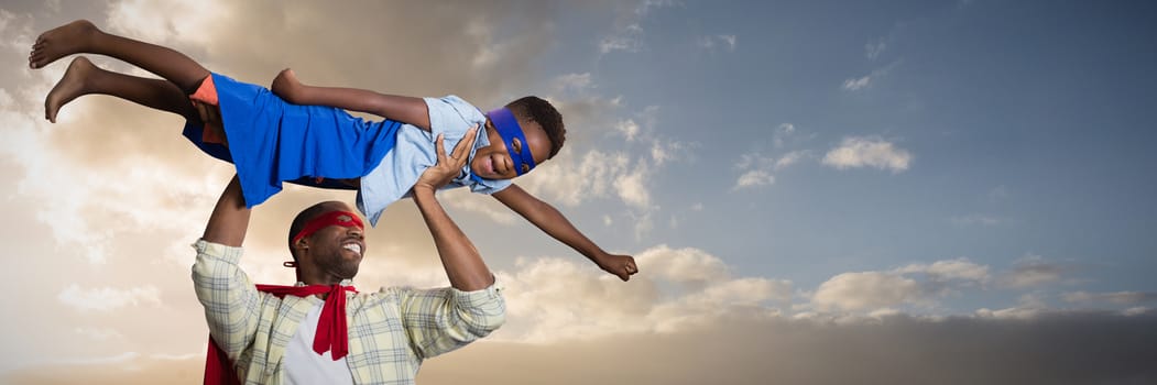 Father and son pretending to be superhero against cloudy sky landscape