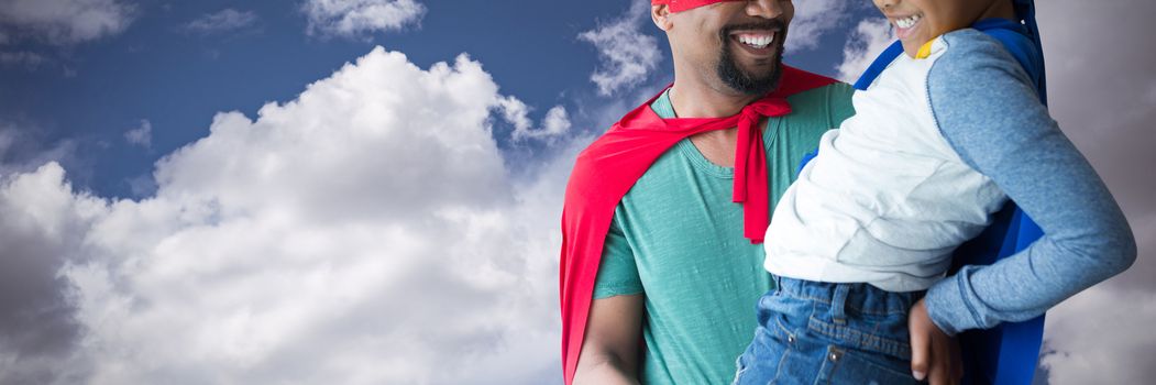 Father and son pretending to be superhero against sky and cloud on a sunny day