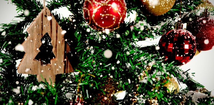 Snow falling against close-up of christmas decorations in tree