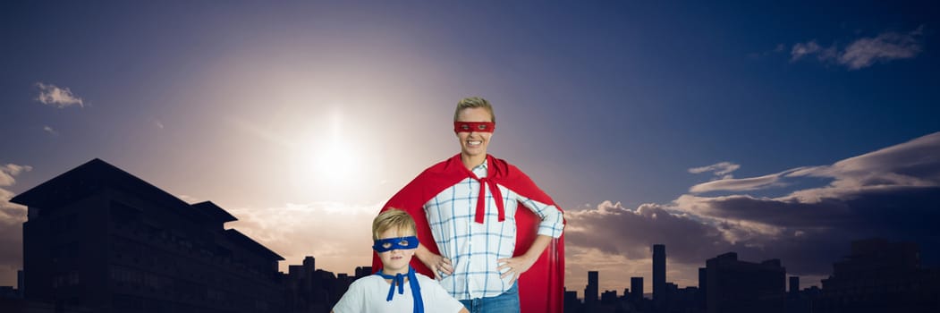 Mother and son pretending to be superhero against picture of city by sunrise