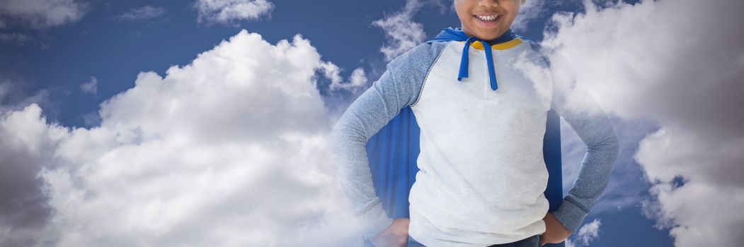Boy pretending to be superhero against sky and cloud on a sunny day