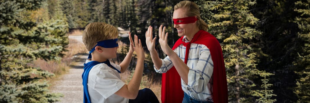 Mother and son pretending to be superhero against road through forest
