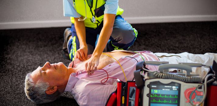 Paramedic using an external defibrillator on an unconscious patient lying on carpet
