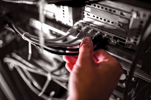 Close-Up of technician plugging patch cable in a rack mounted server in server room
