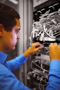 Technician checking cables in a rack mounted server in server room