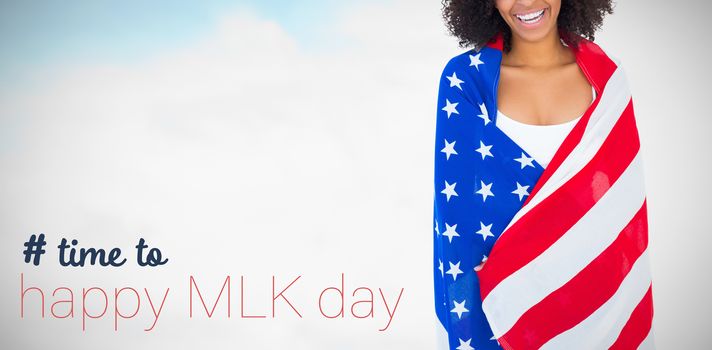 Pretty girl wrapped in american flag smiling at camera against blue sky with clouds 