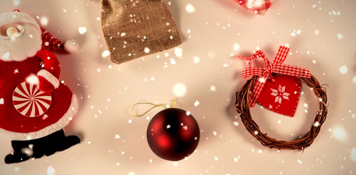 Snow falling against santa, christmas ball and ornaments