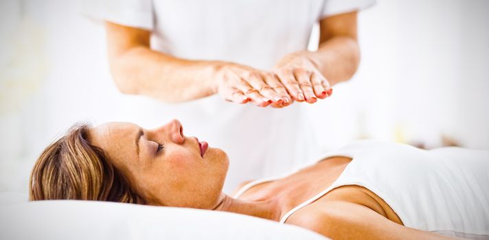 Young woman receiving reiki treatment at spa