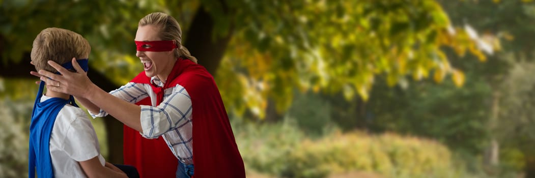 Mother and son pretending to be superhero against tree by footpath