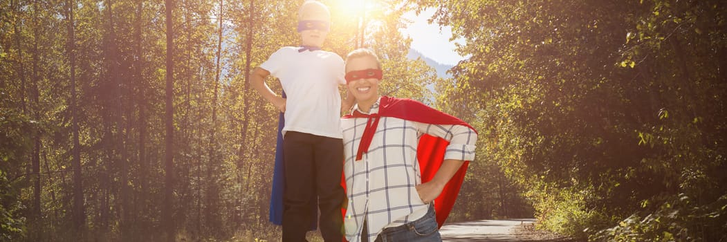 Mother and son pretending to be superhero against road passing through forest
