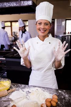Female chef showing her messy hands in kitchen at hotel