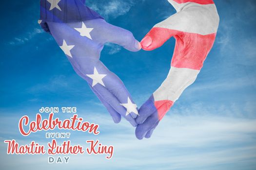 USA flag painted on hands making heart shape against low angle of cloudy sky 
