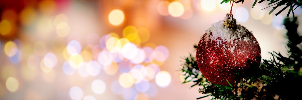 Christmas yellow circle lights against christmas ball hanging in tree covered in snow