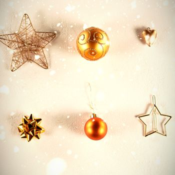 Snow falling against yellow and golden christmas ornaments