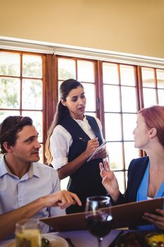 Waitress taking food order from business people in restaurant