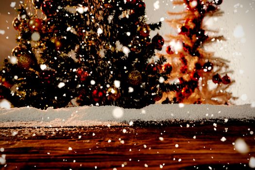 Snow falling against wooden table with snow and christmas tree