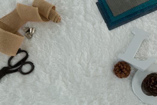 Overhead of textile and pine cone on white background