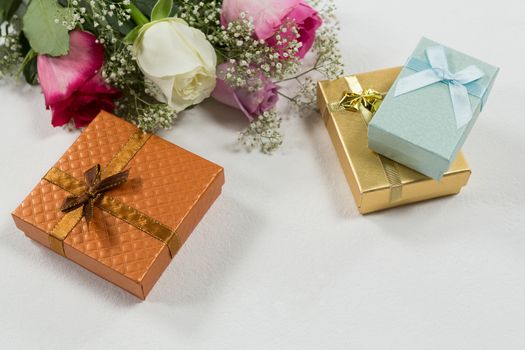 Close-up of flower bouquet and gift on white background